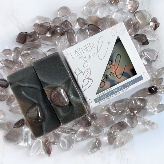 An artisan crystal soap by Lather and Soul Skincare is colored black and brown and sits on a pile of smoky quartz crystals.