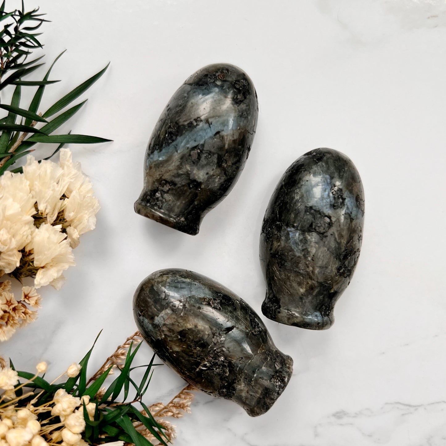 Revealing the Hidden Beauty of Larvikite: A captivating image revealing the backside of three Larvikite crystal vulva shapes, showcasing the stunning blue flash that dances across their surface.