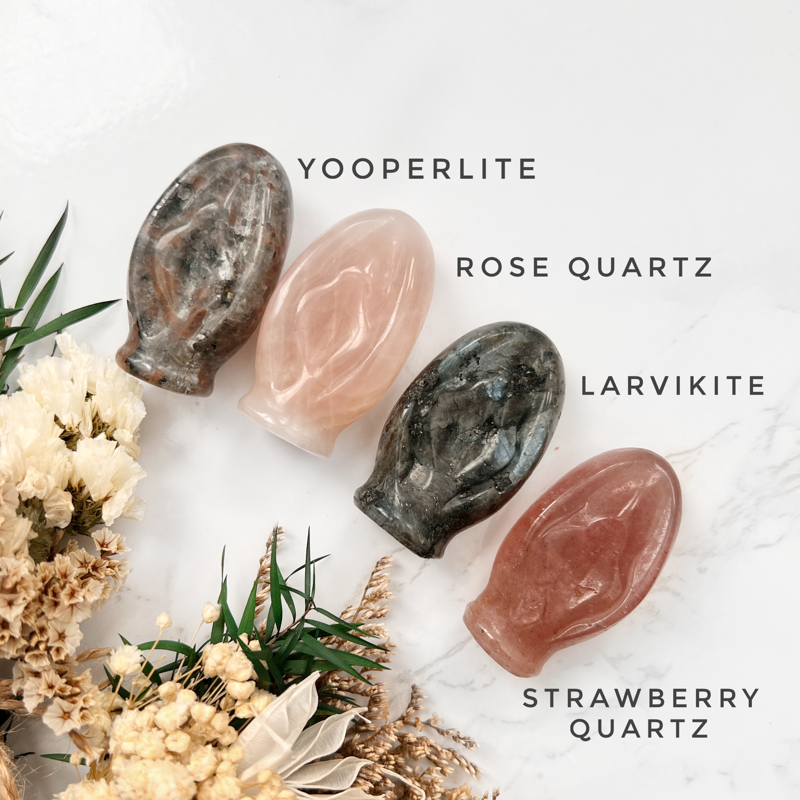 Discover the Feminine Power of 'Source of Life' Crystals: An informative display featuring four crystal vulva shapes—Rose Quartz, Strawberry Quartz, Larvikite, and Yooperlite—each labeled for easy identification. This image invites you to explore the unique properties of each gemstone while embracing the symbolic significance of these crystals as a celebration of femininity, empowerment, and the sacred source of life.