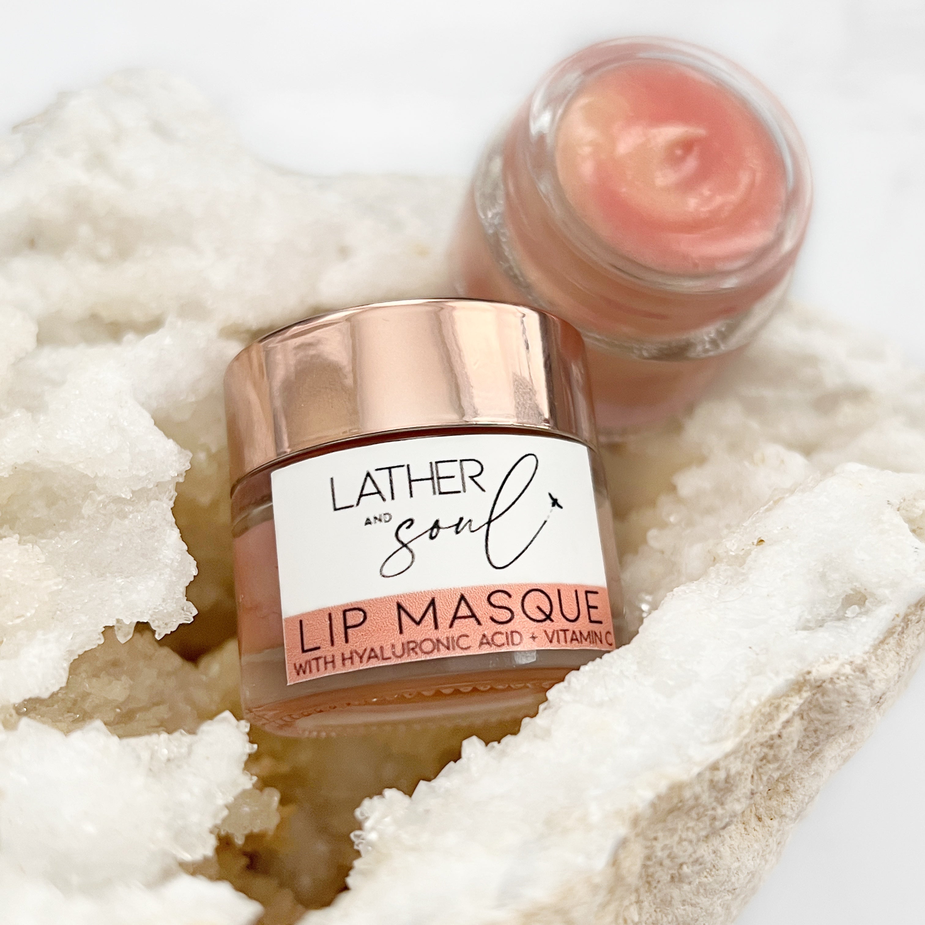 A Duo of Delight: Our Hydrating Lip Masque jars are beautifully showcased—one sealed with an elegant rose gold cap, the other open to reveal its creamy, nourishing texture. This image captures the sophistication and luxurious nature of our lip treatment, inviting customers to experience its hydrating benefits firsthand.