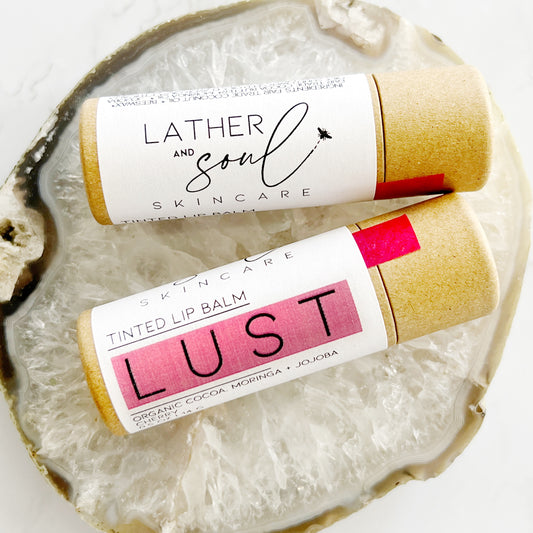 "Lust" pink tinted lip balm in paperboard tube.