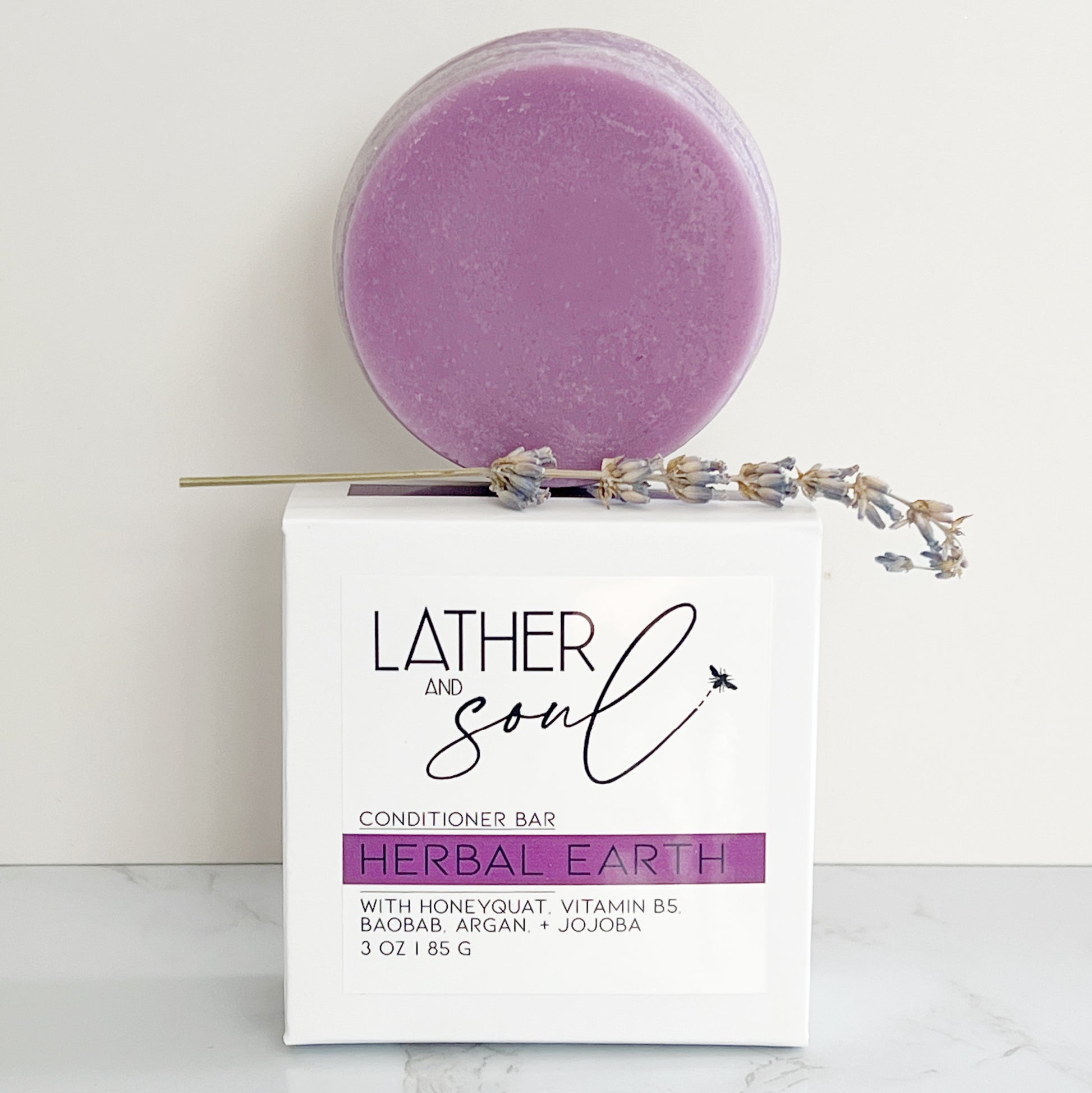 Eco friendly solid conditioner bar from Lather and Soul on wooden dish on marble table.