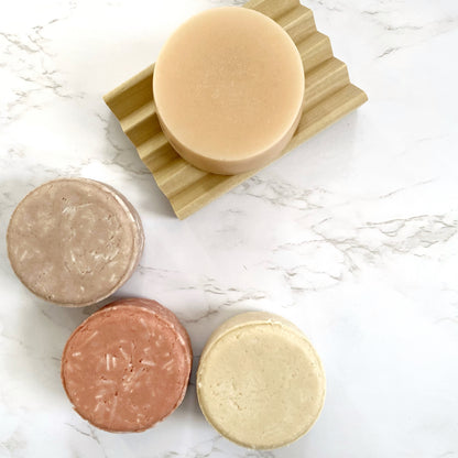 Lather and Soul's solid natural solid shampoo and conditioner bars sit on a table side by side.